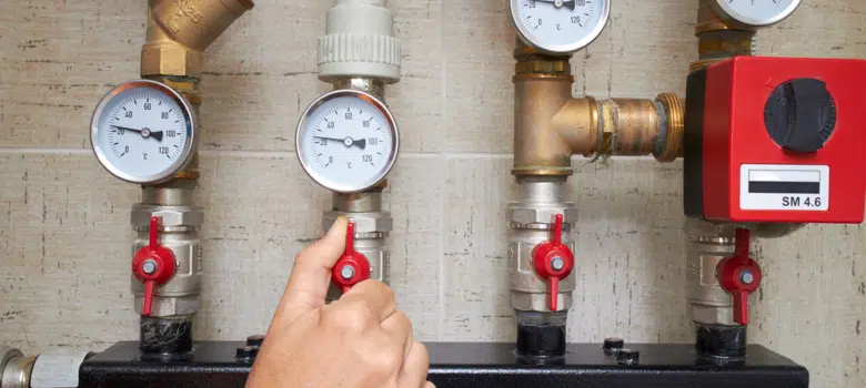 Photo of a person looking at the pressure guages and moving a valve to change the water presure.